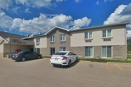 The Village Inn Elora is a two-storey grey brick building with rooms on each level. Street level rooms has sliding glass doors. The second storey rooms have large windows. All rooms overlook the parking area.